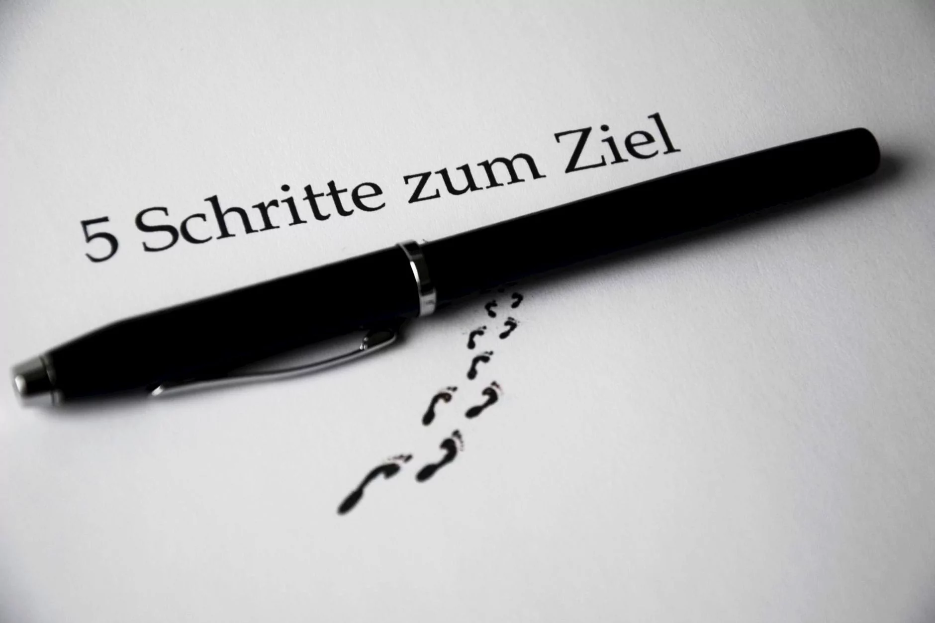 A black pen on a paper with text and footprint visual elements for a conceptual theme.
